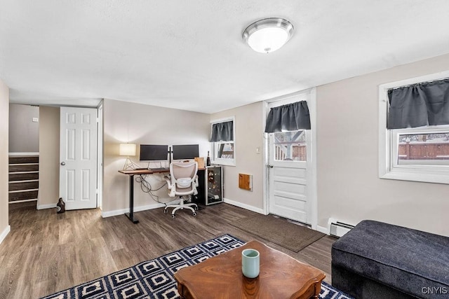 office area with a baseboard radiator, wood finished floors, and baseboards