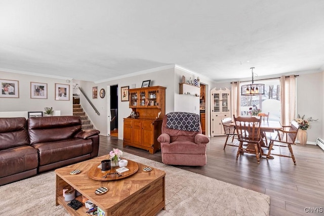 living room with a chandelier, wood finished floors, baseboards, stairs, and ornamental molding