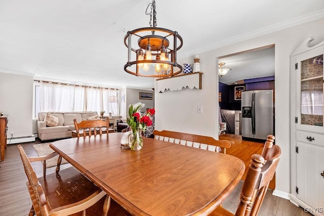 dining room with crown molding, baseboard heating, wood finished floors, and an inviting chandelier