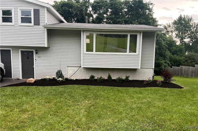 view of side of home featuring a lawn and fence