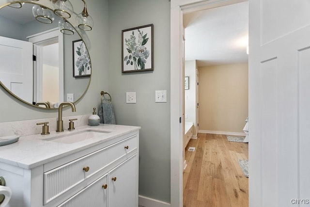 bathroom with baseboards, wood finished floors, and vanity