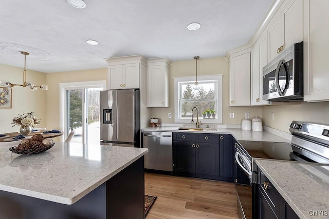 kitchen featuring stainless steel appliances, a sink, white cabinetry, and pendant lighting