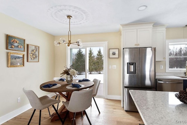 dining room featuring a chandelier, light wood finished floors, and baseboards