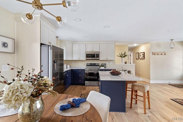 kitchen featuring appliances with stainless steel finishes, blue cabinets, white cabinets, and a kitchen breakfast bar