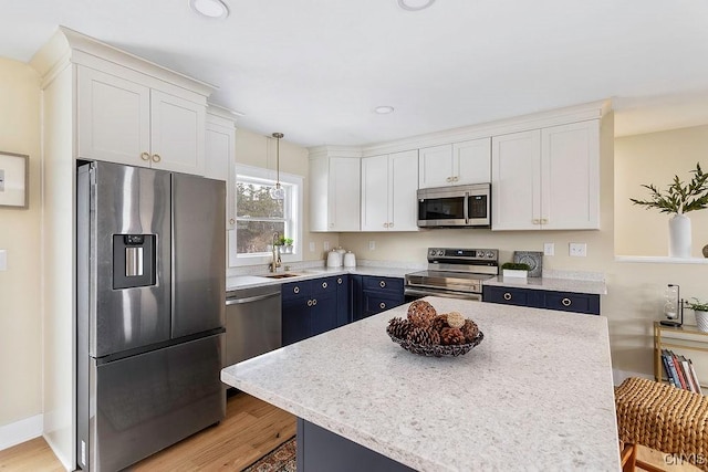 kitchen with stainless steel appliances, blue cabinetry, decorative light fixtures, and white cabinets