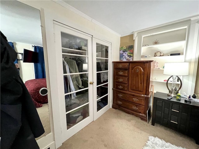 doorway with ornamental molding, french doors, and light carpet