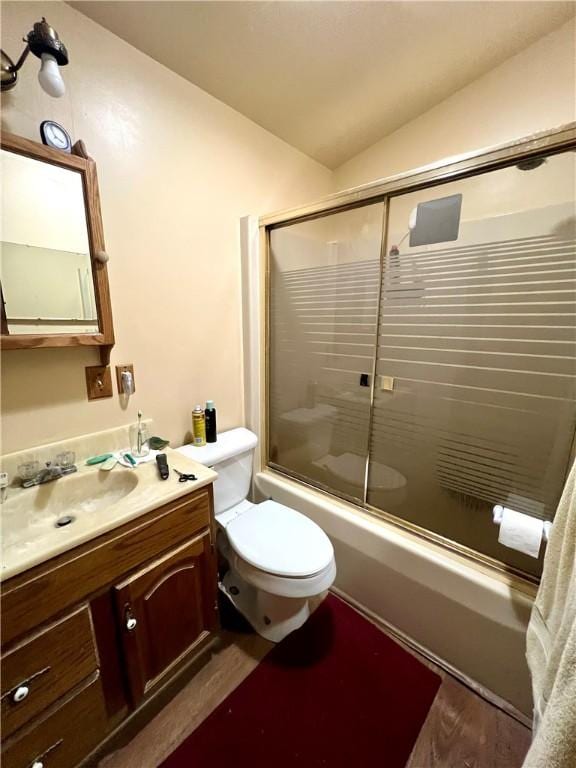 full bath featuring lofted ceiling, toilet, wood finished floors, combined bath / shower with glass door, and vanity