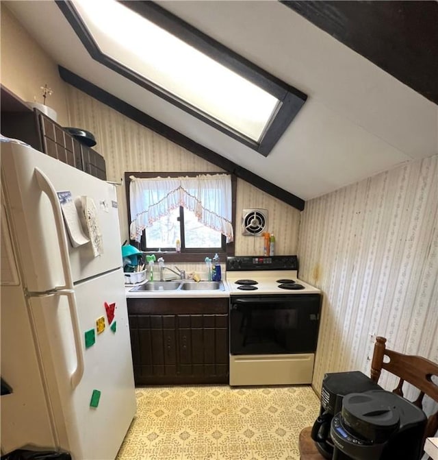 kitchen featuring electric stove, a sink, freestanding refrigerator, and wallpapered walls