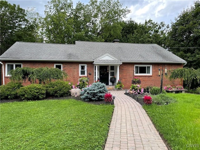 ranch-style house featuring brick siding, a front lawn, and roof with shingles