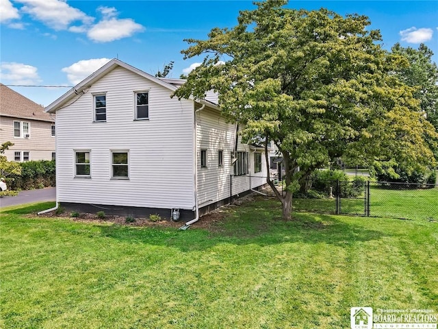 view of side of home featuring fence and a lawn