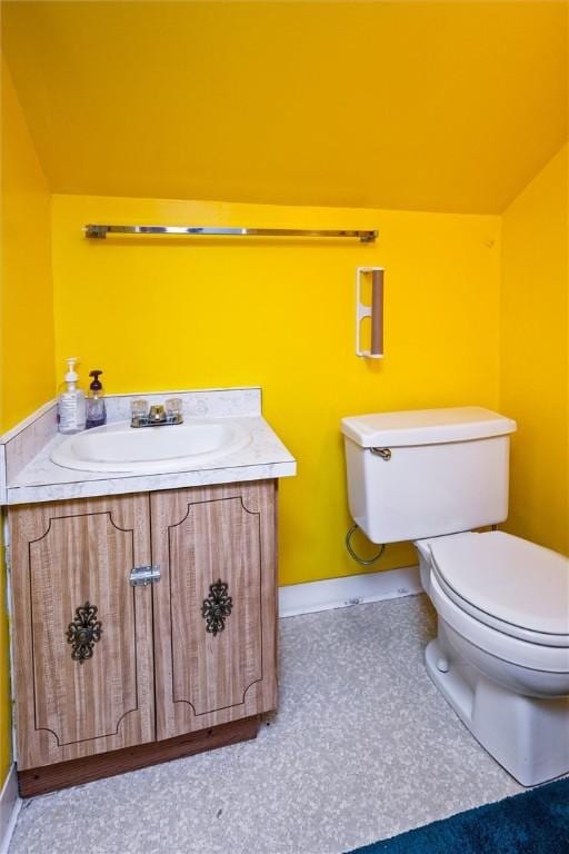 half bath featuring toilet, vanity, and lofted ceiling