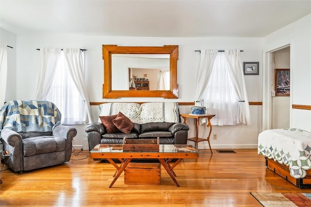 living area featuring light wood-style flooring, visible vents, and baseboards