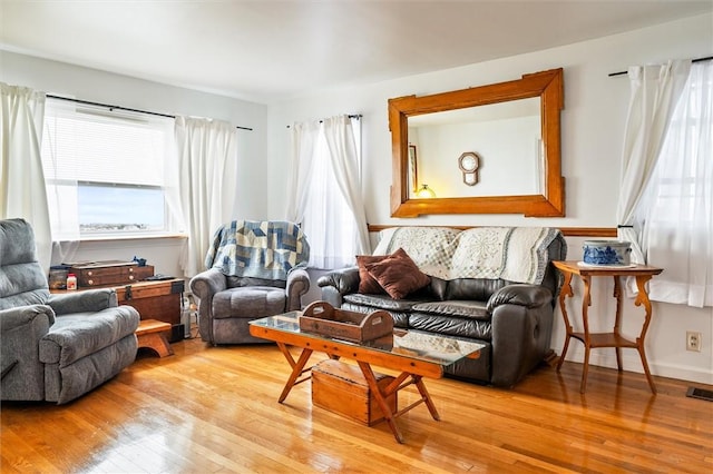 living area with light wood-style floors, visible vents, and a wealth of natural light