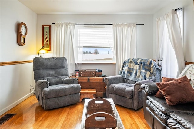 living room with visible vents, baseboards, and wood finished floors