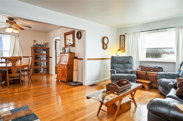 living area featuring baseboards, a healthy amount of sunlight, visible vents, and light wood finished floors