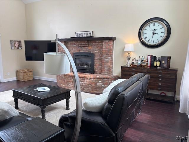 living area featuring a fireplace, wood finished floors, and baseboards