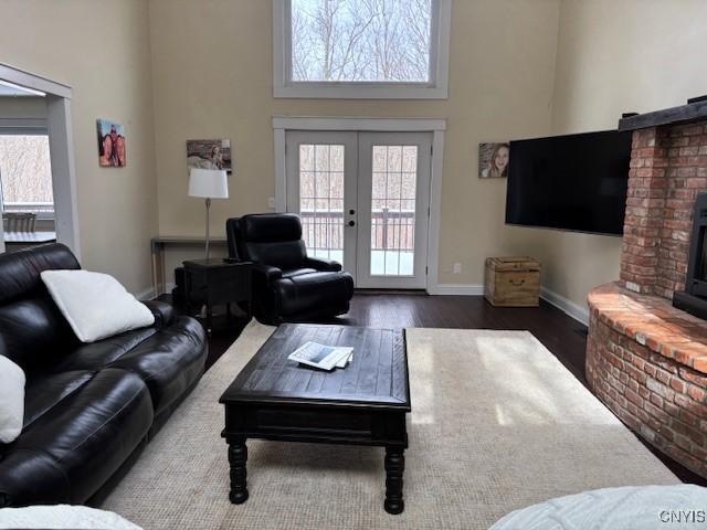 living area featuring a towering ceiling, a wealth of natural light, wood finished floors, and french doors