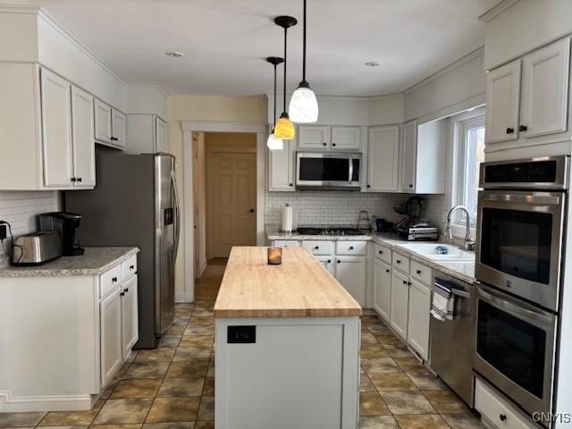 kitchen with a center island, stainless steel appliances, backsplash, a sink, and butcher block countertops