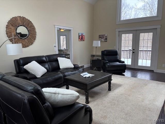 living area with dark wood-style floors, a wealth of natural light, french doors, and a high ceiling