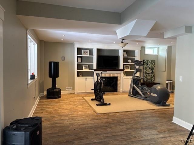 workout area featuring a fireplace, baseboards, wood finished floors, and recessed lighting