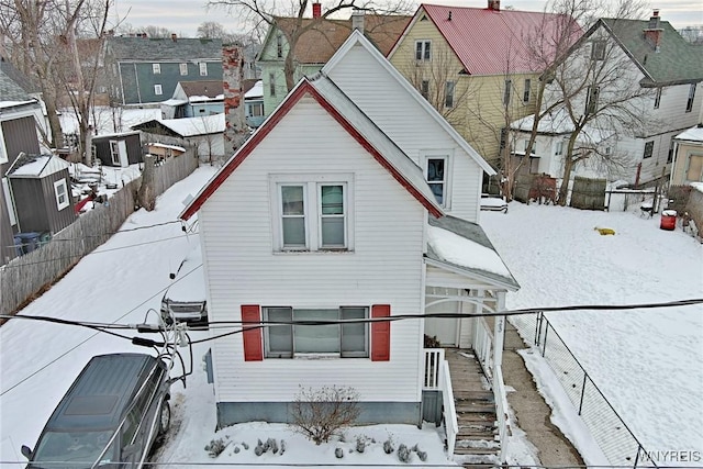 snow covered property featuring fence, a residential view, and central air condition unit