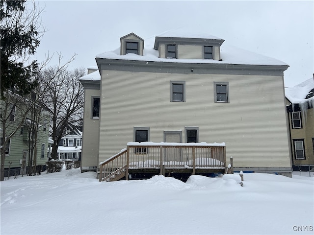 snow covered back of property with a wooden deck