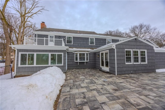 rear view of property featuring a balcony, a patio area, a chimney, and fence