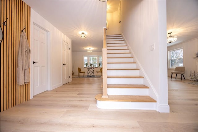 staircase with a healthy amount of sunlight, an inviting chandelier, and wood finished floors