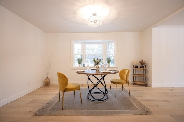 dining space featuring light wood finished floors, an inviting chandelier, and baseboards