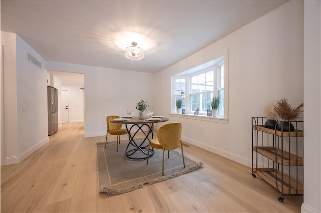 dining space with light wood-style floors, visible vents, and baseboards