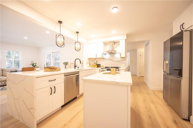 kitchen featuring stainless steel appliances, wall chimney range hood, a kitchen island, and white cabinetry