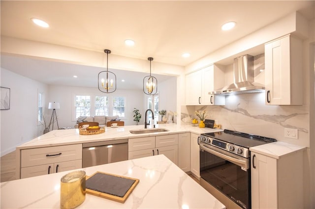 kitchen featuring wall chimney exhaust hood, light stone countertops, stainless steel appliances, white cabinetry, and a sink