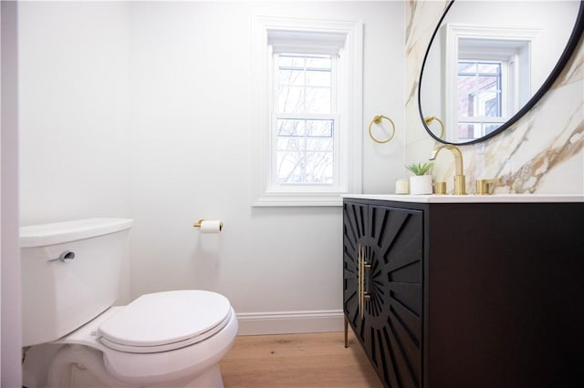 half bathroom featuring vanity, wood finished floors, toilet, and baseboards