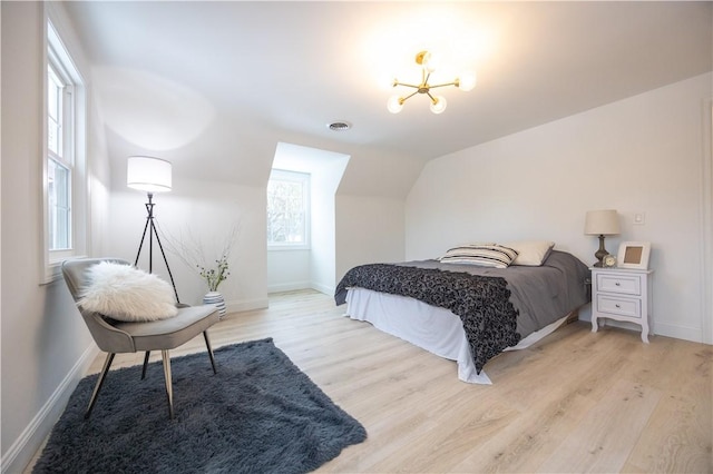 bedroom featuring visible vents, baseboards, lofted ceiling, light wood-type flooring, and a notable chandelier