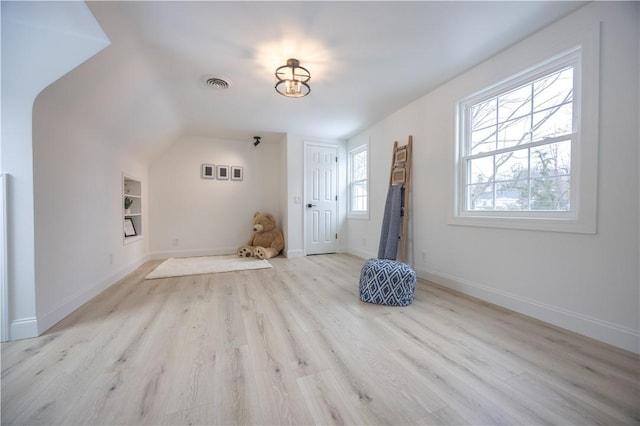 bonus room with light wood finished floors, baseboards, built in shelves, and visible vents