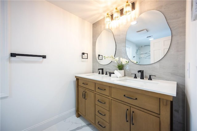 bathroom featuring double vanity, marble finish floor, baseboards, and a sink