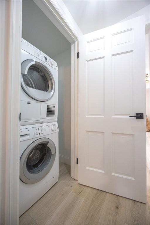 clothes washing area with laundry area, light wood-style floors, and stacked washer / drying machine