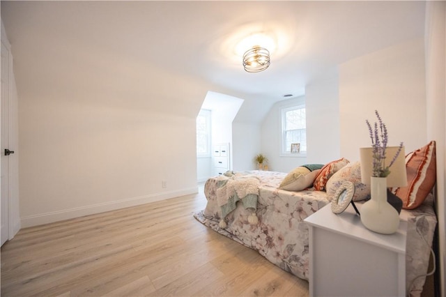 bedroom featuring light wood-style floors, vaulted ceiling, and baseboards