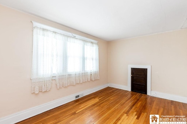 empty room featuring hardwood / wood-style flooring, baseboards, and visible vents