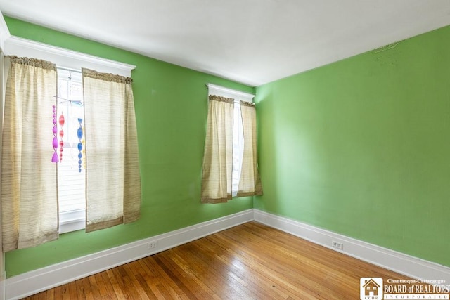 unfurnished room featuring a healthy amount of sunlight, hardwood / wood-style flooring, and baseboards