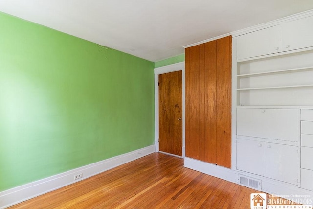 unfurnished bedroom featuring baseboards, a closet, visible vents, and light wood-style floors