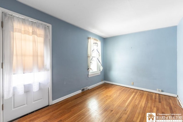 unfurnished room featuring visible vents, baseboards, and hardwood / wood-style flooring