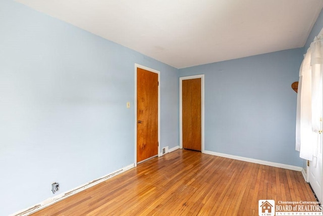 unfurnished room with light wood-type flooring, visible vents, and baseboards