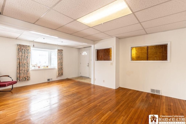 spare room featuring hardwood / wood-style floors, a drop ceiling, and visible vents