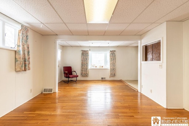 interior space featuring a paneled ceiling, light wood-style floors, and visible vents