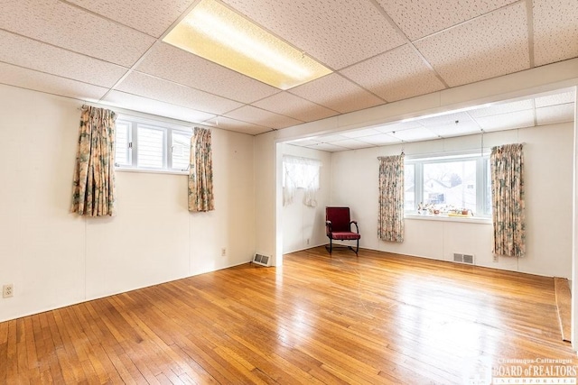 unfurnished room featuring hardwood / wood-style flooring, visible vents, and a drop ceiling