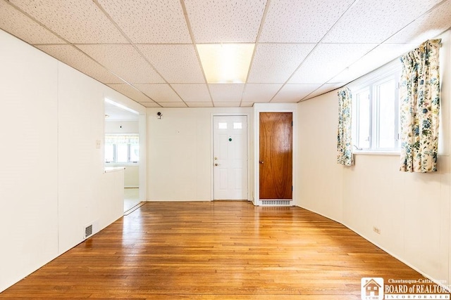 spare room featuring a paneled ceiling, visible vents, and light wood finished floors