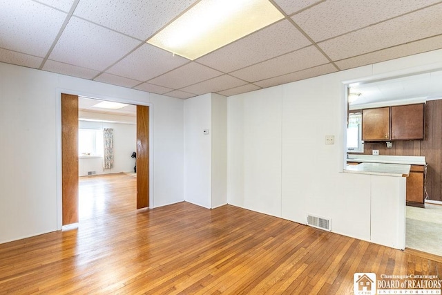 unfurnished room featuring light wood finished floors, a drop ceiling, and visible vents