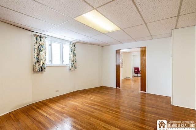 spare room with a paneled ceiling, visible vents, and wood finished floors