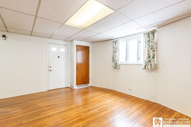 unfurnished room with a paneled ceiling and light wood-style floors